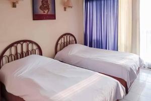 due letti uno accanto all'altro in una camera da letto di RedDoorz Plus near Tugu Mercusuar Anyer a Serang Altre 21 foto
