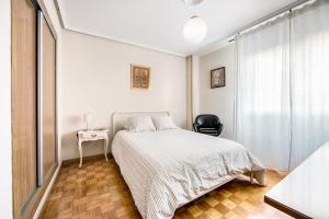 biała sypialnia z łóżkiem i krzesłem w obiekcie Magnifico apartamento en el centro de Oviedo w mieście Oviedo