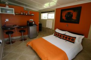 1 dormitorio con paredes de color naranja, 1 cama y barra. en Haus Holzapfel, en Beaufort West