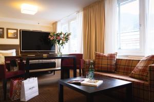 a living room with a tv and a couch and a table at Hotel Stadt Kufstein in Kufstein