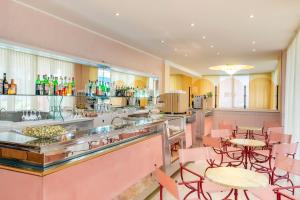 un restaurante con mesas y sillas rosas y un bar en Hotel Souvenir, en Bellaria-Igea Marina