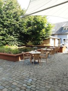 eine Terrasse mit Tischen, Stühlen und einem Sonnenschirm in der Unterkunft T Karraet in Maasmechelen