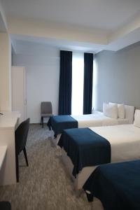 una habitación de hotel con tres camas y un escritorio en Glass Cube Hotel, en Chişinău