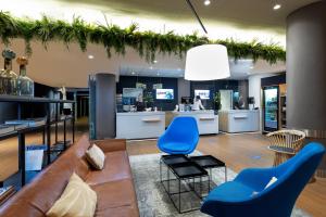 ein Wohnzimmer mit einem Sofa und blauen Stühlen in der Unterkunft Novotel The Hague World Forum in Den Haag