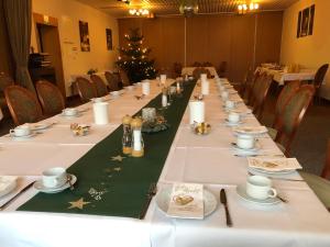 una mesa larga en una habitación con un árbol de Navidad en Hotel zum Nordpol en Schenefeld