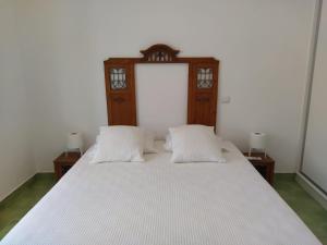1 cama con 2 almohadas blancas y cabecero de madera en Urban Apartment, en Faro