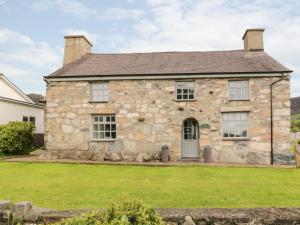 una antigua casa de piedra con césped verde en Llwyn Aethnen, en Caernarfon