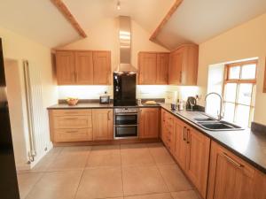 a kitchen with wooden cabinets and a black counter top at Llwyn Aethnen in Caernarfon