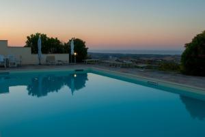 uma piscina com um pôr-do-sol ao fundo em Borghetto Country Apartments em Saludecio