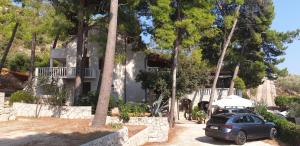 a car parked in front of a house with trees at B&B Pansion Jure Matijević in Sveta Nedelja