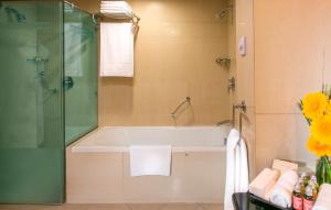 a bathroom with a bath tub and a shower at Swissôtel Al Murooj Dubai in Dubai