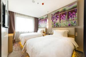 2 letti in una camera d'albergo con fiori sul muro di Lavande Hotels Weihai Weigao Square Branch a Weihai