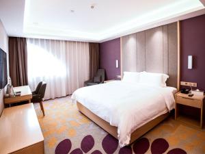 a hotel room with a large bed and a desk at Lavande Hotel (Gaozhou Xiantai Bridge Branch) in Maoming
