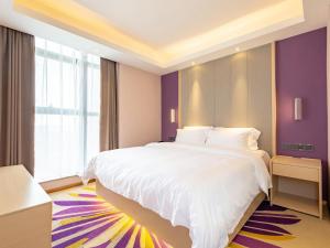 una camera da letto con un grande letto bianco e pareti viola di Lavande Hotel Nanchang Qingyunpu Zhuqiao East Road a Nanchang