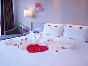 uma cama com dois cisnes vestidos de rosas vermelhas em Lavande Hotel (Harbin Ice and Snow World University of Commerce Branch) em Harbin