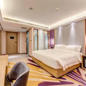 Lavande Hotel Tangshan Convention and Exhibition Yuanyang City في تانغشان: غرفة نوم بسرير كبير وكرسي