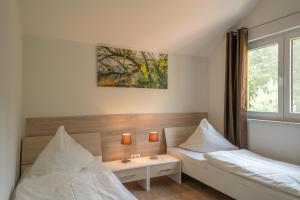 a bedroom with two beds and a table with two lamps at Ferienhaus Rübezahl am Müggelsee in Berlin
