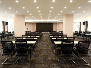 Lavande Hotel Jiujiang Jiujiang College في Jiujiang: غرفة كبيرة بها طاولات وكراسي وشاشة
