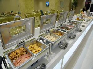una línea de buffet con bandejas de comida en una mesa en Lavande Hotel Jilin Songjiang Road Jiangwan Bridge Branch en Jilin