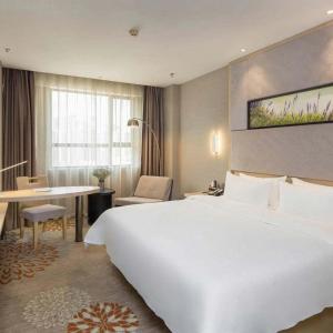 a hotel room with a large white bed and a desk at Lavande Hotel Changsha High-speed Railway Station Shuling in Changsha