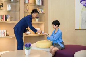 a woman helping a young boy in a room at Lavande Hotel (Changsha City Government Branch) in Changsha