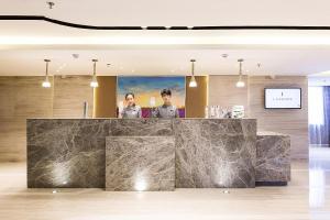 two people standing behind a marble counter in a lobby at Lavande Hotels Weihai Weigao Square Branch in Weihai