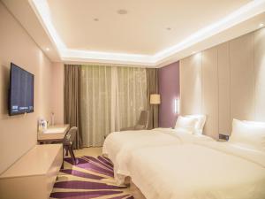 CangzhouにあるLavande Hotel Cangzhou Kaiyuan Avenue Rongsheng Plazaのベッド2台とデスクが備わるホテルルームです。