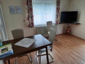 a dining room with a table and chairs and a television at Haus am Schroffen in Ottenhöfen