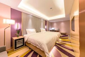 - une chambre avec un grand lit et une télévision dans l'établissement Lavande Hotel (Qinhuangdao Yingbin Road Railway Station Branch), à Qinhuangdao