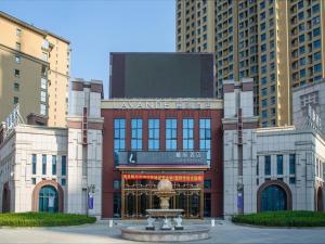 Lavande Hotel Cangzhou Kaiyuan Avenue Rongsheng Plaza في Cangzhou: مبنى كبير أمامه نافورة