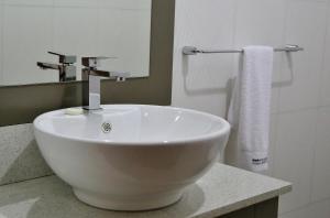 a white sink in a bathroom with a mirror at Alisa Hotel North Ridge in Accra