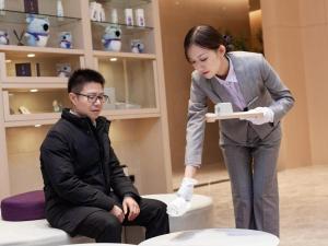 Una mujer le está entregando una caja a un hombre. en Lavande Hotel Changsha Avenue Metro Station, en Changsha