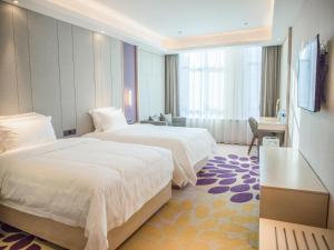 CangzhouにあるLavande Hotel Cangzhou Kaiyuan Avenue Rongsheng Plazaのベッド2台とデスクが備わるホテルルームです。