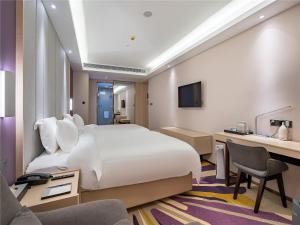 a hotel room with a large white bed and a desk at Lavande Hotel Xuzhou Junsheng Plaza in Xuzhou