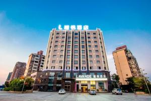 un edificio alto con auto parcheggiate in un parcheggio di Lavande Hotel Nanchang Qingshanhu Wanda Branch a Nanchang