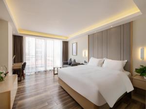 a bedroom with a large white bed and a desk at Lavande Hotel Haikou Binhai Avenue in Haikou