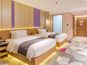 twee bedden in een kamer met paarse en paarse muren bij Lavande Hotel Lujiang Zhouyu Avenue in Lujiang