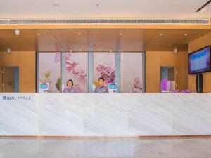 two people standing behind a counter in a building at Lavande Hotel (Binzhou Huanghe 8th Road, People's Hospital Branch) in Binzhou