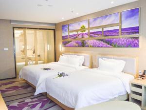 徐州市にあるLavande Hotel Xuzhou New Town Midea Plazaの壁に絵画が飾られたホテルルーム内のベッド2台