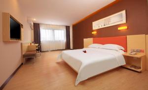 - une chambre avec un grand lit blanc et une télévision à écran plat dans l'établissement 7 Days Premium Jiaozuo Renmin Road Teachers College, à Jiaozuo