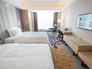 a hotel room with two beds and a desk at Lavande Hotel Zhongshan Nanlang Light Rail Station in Zhongshan