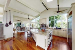 a large kitchen with white cabinets and a hardwood floor at Punahele home in Princeville