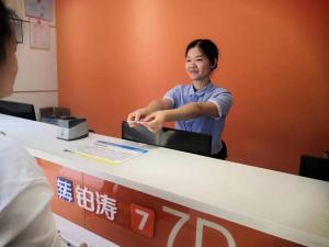 a woman standing in front of a reception desk at 7Days Inn Yongzhou Central Hospital in Yongzhou