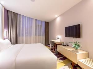 um quarto de hotel com uma cama, uma secretária e uma televisão em Lavande Hotel Changsha Xingsha Center em Xingsha