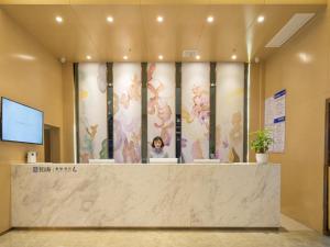 un vestíbulo con un mostrador de recepción con flores en la pared en Lavande Hotel Jingmen Planet World City, en Jingmen