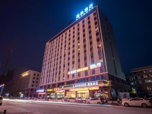 um edifício iluminado com carros estacionados em frente em Lavande Hotel(Macheng High-speed Station Branch) em Macheng