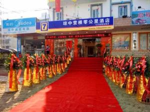 un lungo tappeto rosso con sopra persone in costume arancione di 7Days Inn Qiongzhong Zero Kilometer a Qiongzhong