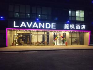 徐州市にあるLavande Hotel Xuzhou New Town Midea Plazaの夜の読み取り用の看板のある建物