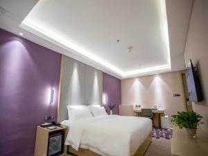 sypialnia z białym łóżkiem i fioletową ścianą w obiekcie Lavande Hotel Jinzhou Jiefang Road Kaixuan Building w Jinzhou