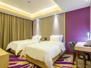 two beds in a hotel room with purple walls at Lavande Hotel Qiqihar Supervisory Office in Qiqihar
